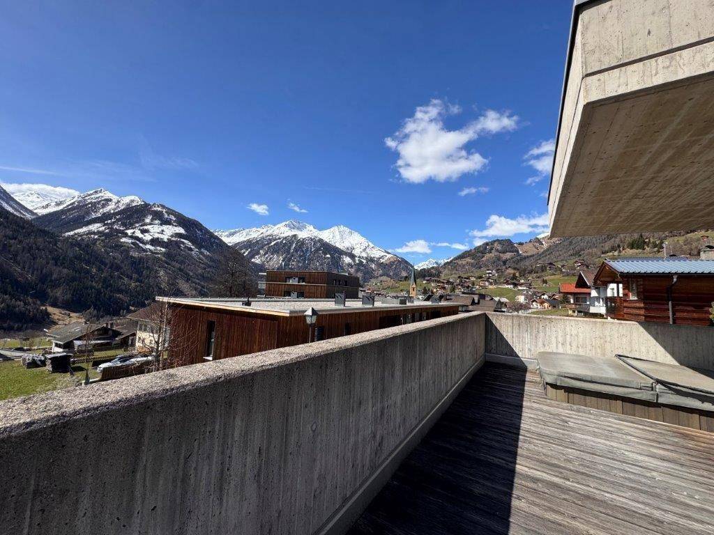 Sonniger Terrassenbereich mit Whirlpool und beeindruckendem Panoramablick auf die schneebedeckten Berge.