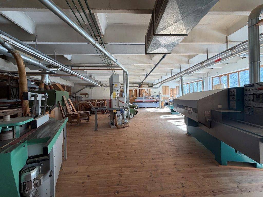 Großer Werkstattbereich mit Holzbearbeitungsmaschinen, hohen Decken und reichlich Tageslicht.