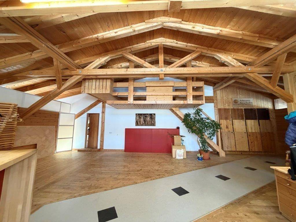 Geräumiger Werkstattbereich mit sichtbaren Holzdeckenbalken, Holzboden und viel Tageslicht.