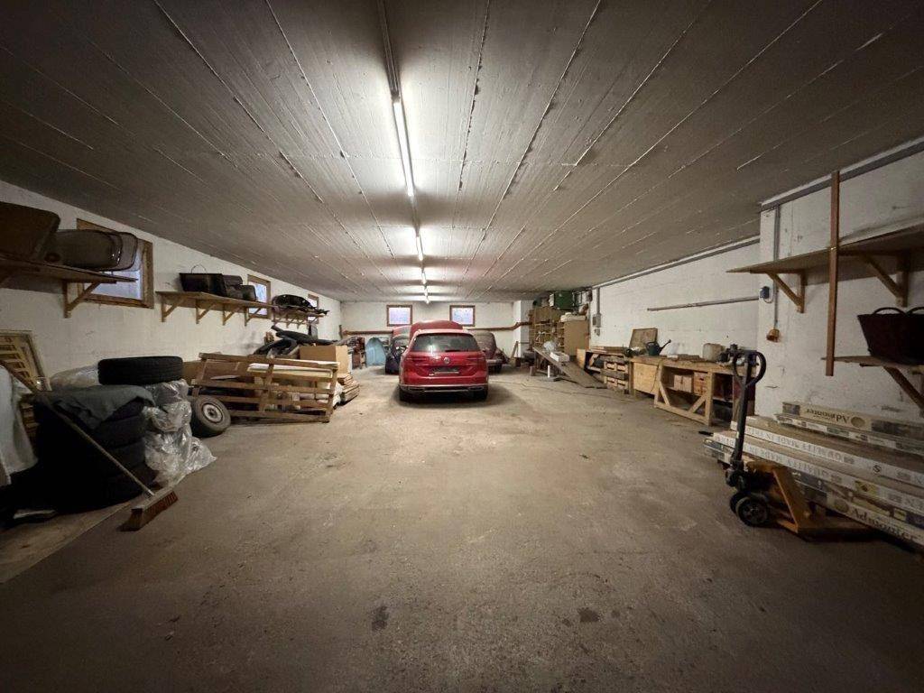 Geräumige Garage oder Lagerhalle mit Betonboden und einem geparkten Fahrzeug im hinteren Bereich.