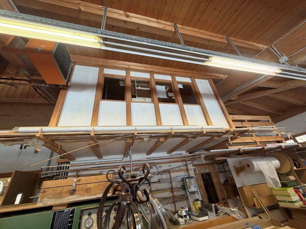 Detailansicht einer erhöhten Holzkonstruktion in einem Werkstattraum mit industrieller Beleuchtung.