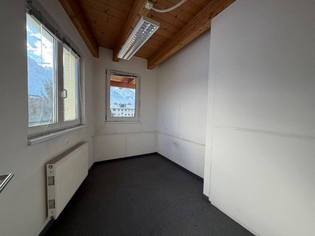 Kleinerer Büroraum mit Holzbalkendecke, Teppichboden und Fenstern mit Bergblick.