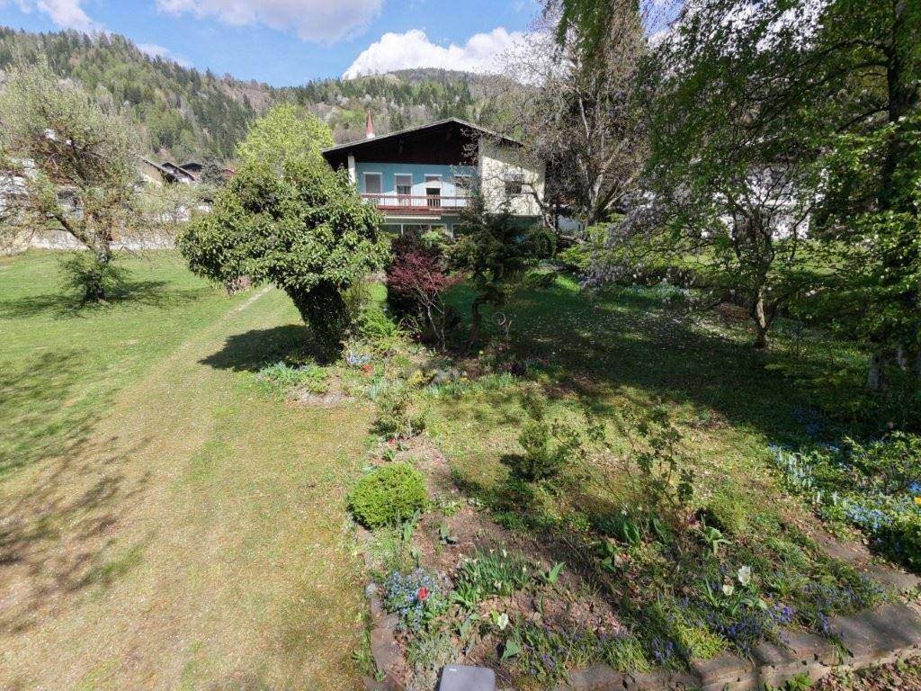 Weitläufiger Gartenbereich mit altem Baumbestand und Blick auf das Haus und die umliegende Natur.