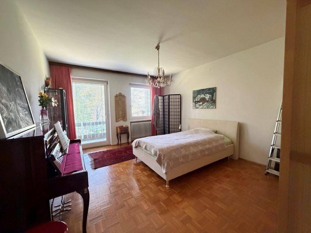 Geräumiges Schlafzimmer mit Parkettboden, Doppelbett und Zugang zu einem französischen Balkon.