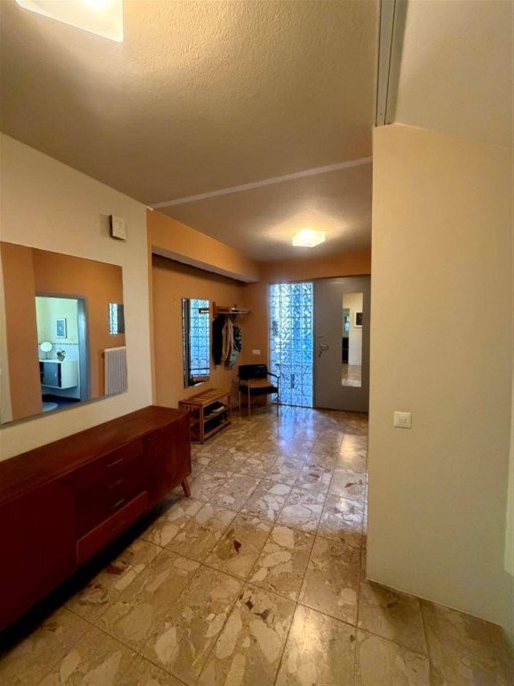 Eingangsbereich mit Fliesenboden, Spiegel und Garderobe, hell und einladend gestaltet.