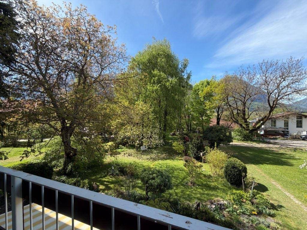 Weitläufiger Blick vom Balkon auf den grünen Garten und die umliegende Berglandschaft.