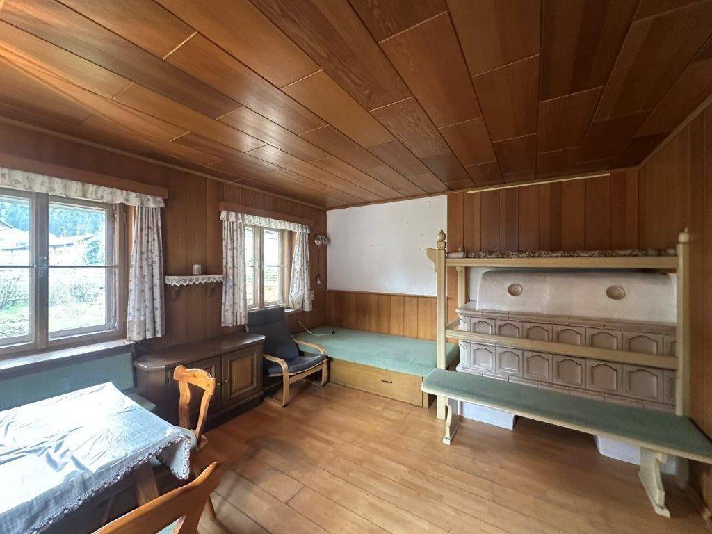 Traditionelles alpenländisches Wohnzimmer mit Holztäfelung, Kachelofen und rustikalem Essbereich.
