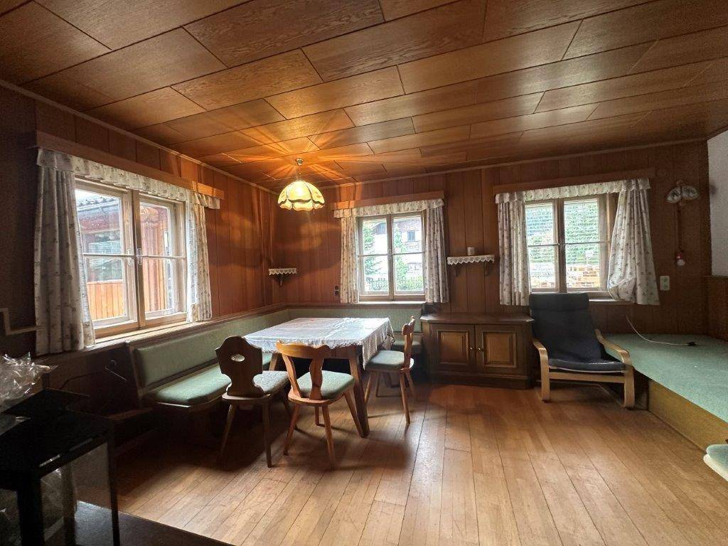 Traditionelles Wohnzimmer im Alpenstil mit Holztäfelung, Essbereich und gemütlicher Eckbank.