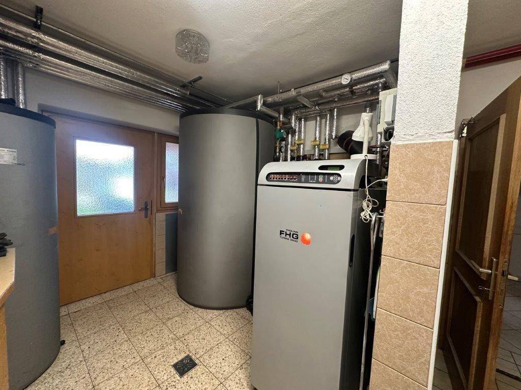 Heizungsraum mit modernem Heizsystem, Warmwasserspeichern und Fliesenboden.