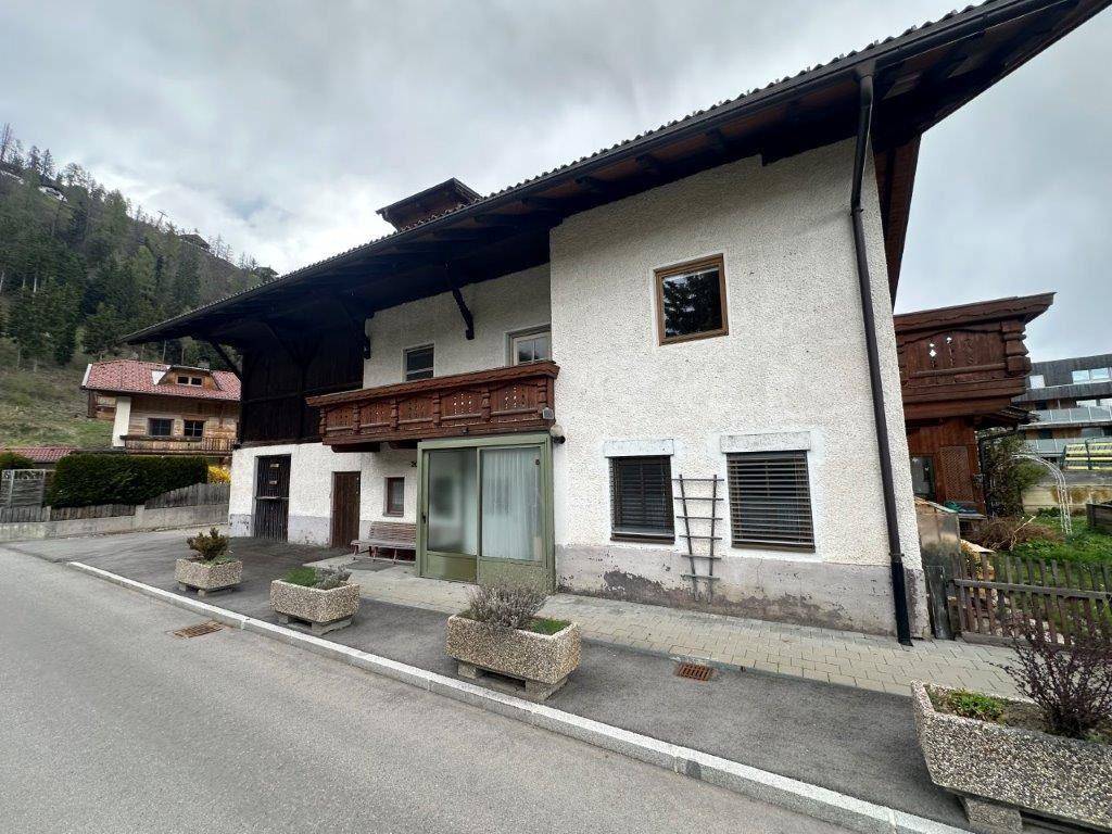 Ansicht des Hauses von der Straße mit Balkon und dekorativen Pflanzkübeln.