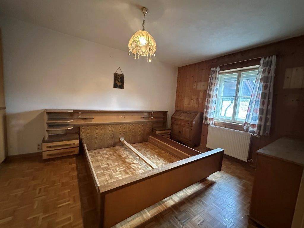 Schlafzimmer mit traditionellen Holzmöbeln, holzgetäfelten Wänden und Parkettboden.