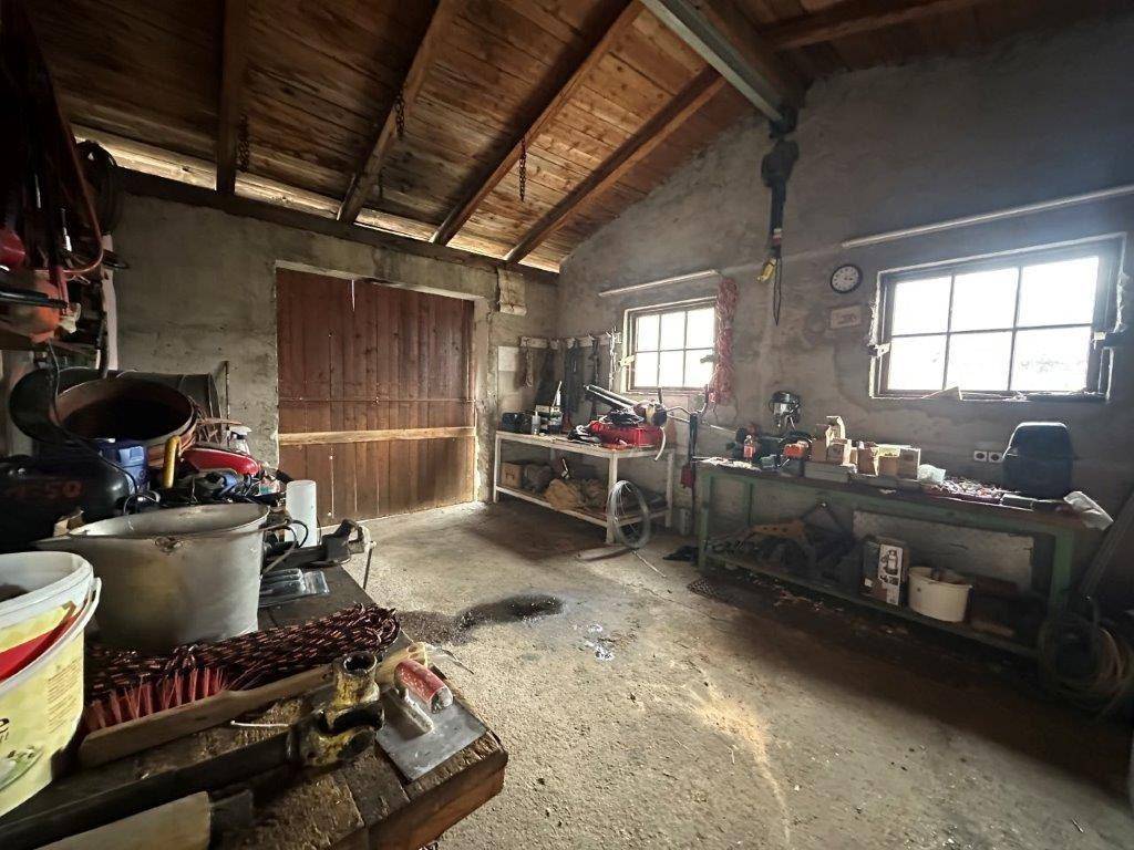 Werkstatt oder Garagenbereich mit Werkzeugen, Werkbänken und einem großen Holztor.