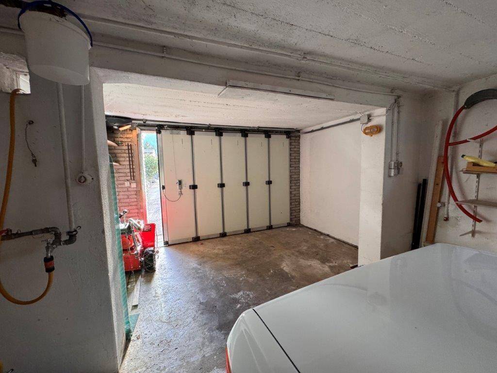 Geräumige Garage mit Betonboden und Falttor, bietet Platz für ein Fahrzeug.
