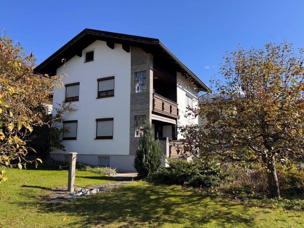 Vorderansicht des Wohnhauses mit gepflegtem Garten, Bäumen und traditioneller Architektur.