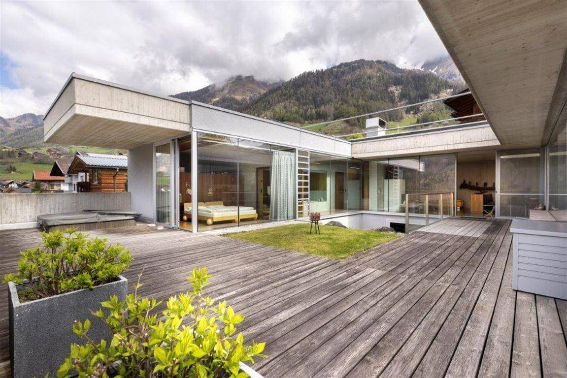 Weitläufige Dachterrasse mit Holzboden, Whirlpool und Panoramablick auf die umliegenden Berge.