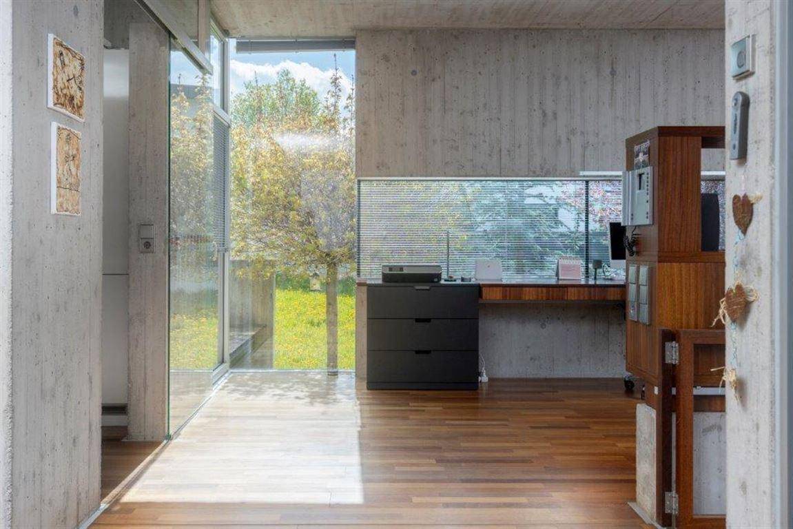 Helles Arbeitszimmer mit Holzboden, großen Fenstern und Blick ins Grüne.