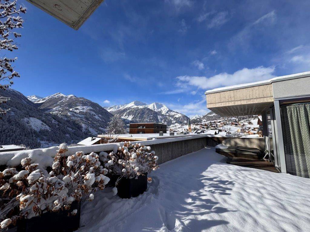 Verschneite Dachterrasse mit atemberaubendem Panoramablick auf die winterliche Berglandschaft.