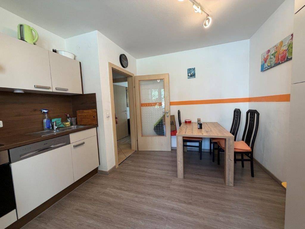 Funktionale Küche mit Holztheke, Essbereich und Zugang zu einem weiteren Raum.