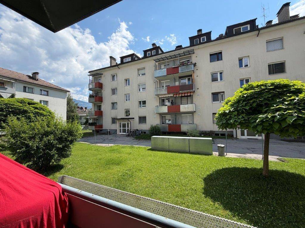 Mehrfamilienhaus mit mehreren Balkonen und einer gepflegten Grünfläche im Vordergrund.