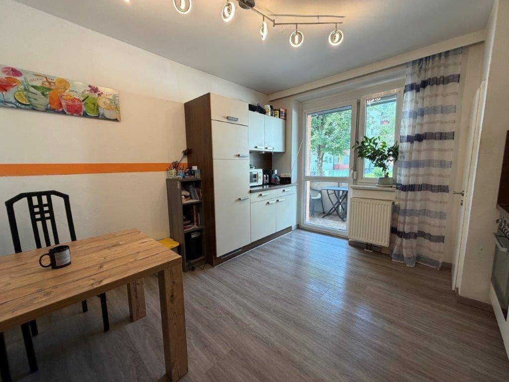 Kleine Küche mit Essbereich, Laminatboden und Zugang zu einem Balkon.