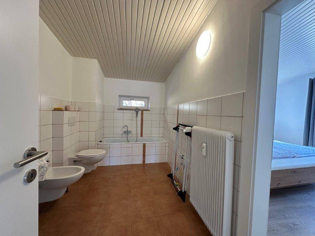 Geräumiges Badezimmer mit Badewanne, Bidet, WC und einem Fenster für frische Luft.