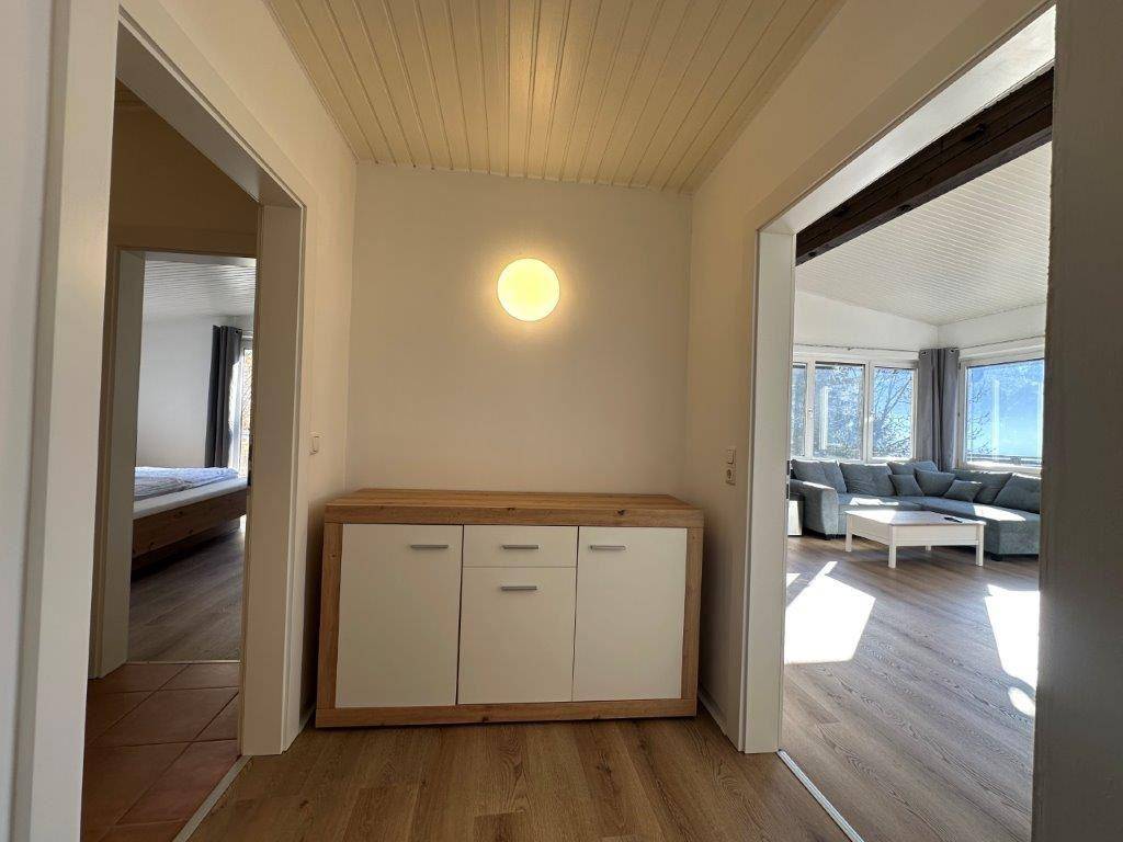 Heller Flurbereich mit modernem Sideboard und Zugang zu Schlafzimmer und Wohnbereich.