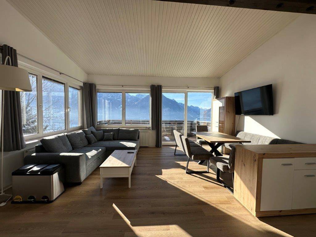 Lichtdurchfluteter Wohn-Essbereich mit Seeblick, gemütlichem Sofa und Holzboden.