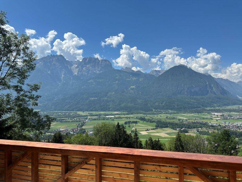 Geräumiger Holzbalkon mit weitem Blick über das Tal und die majestätischen Berge.