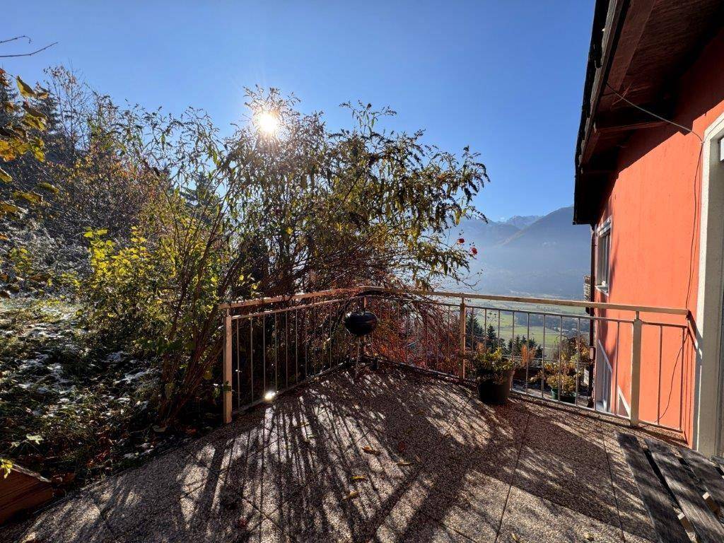 Sonniger Terrassenbereich mit Panoramablick auf das Tal und die umliegenden Berge.