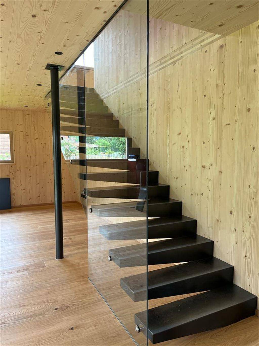 Moderne Treppe mit schwebenden Stufen und Glasgeländer in einem hellen Holzinterieur.