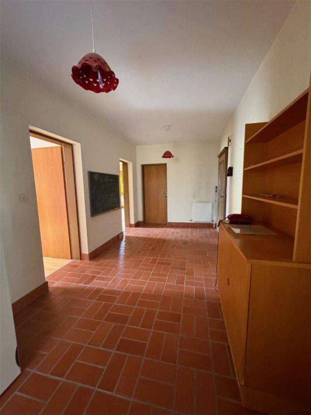 Geräumiger Flur mit Terrakottafliesen und Holztüren, der zu verschiedenen Räumen führt.