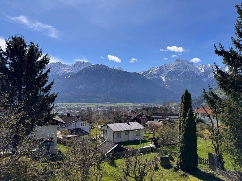Weitläufiger Panoramablick über ein Tal mit Häusern und schneebedeckten Bergen im Hintergrund.