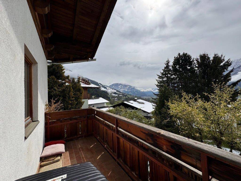 Gemütlicher Balkon mit Holzgeländer und malerischem Blick auf die Berge und das Tal.