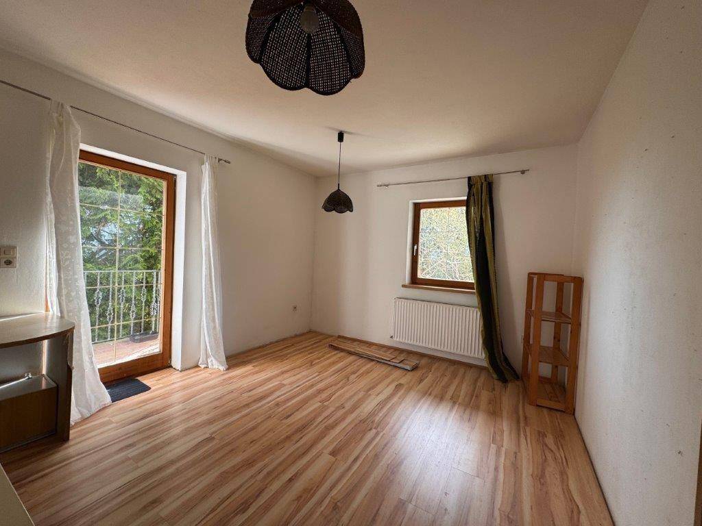 Helles Zimmer mit Holzboden und direktem Zugang zu einem Balkon, ideal für frische Luft.