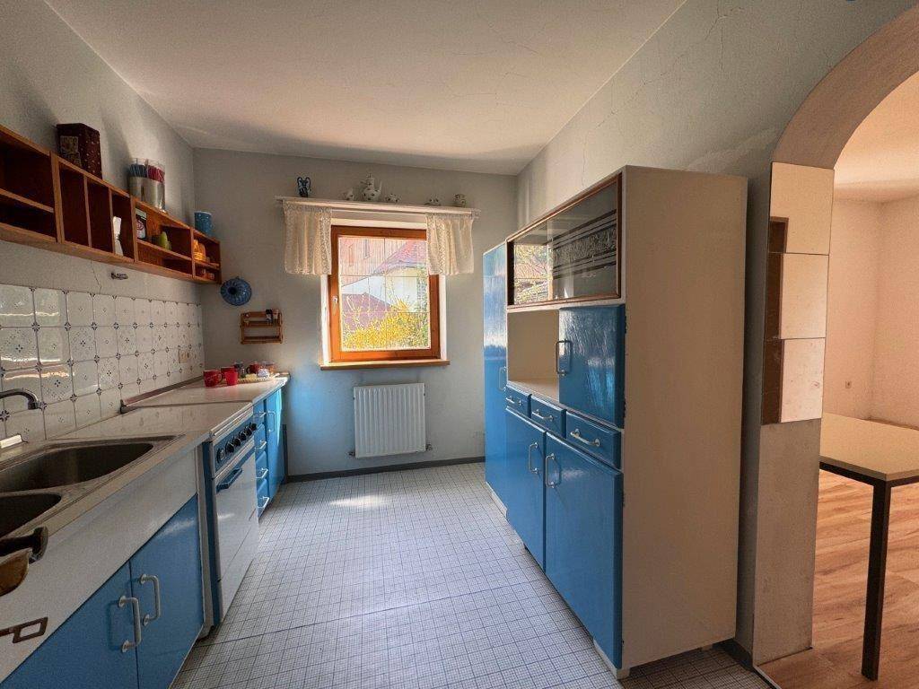 Traditionelle Küche mit blauen Schränken, weiß gefliestem Spritzschutz und Fenster.