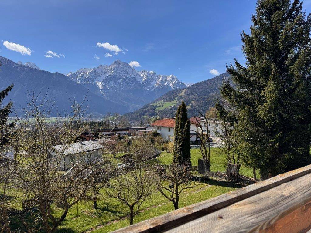 Malerischer Ausblick auf die umliegende Natur mit Gärten, Häusern und majestätischen Bergen.