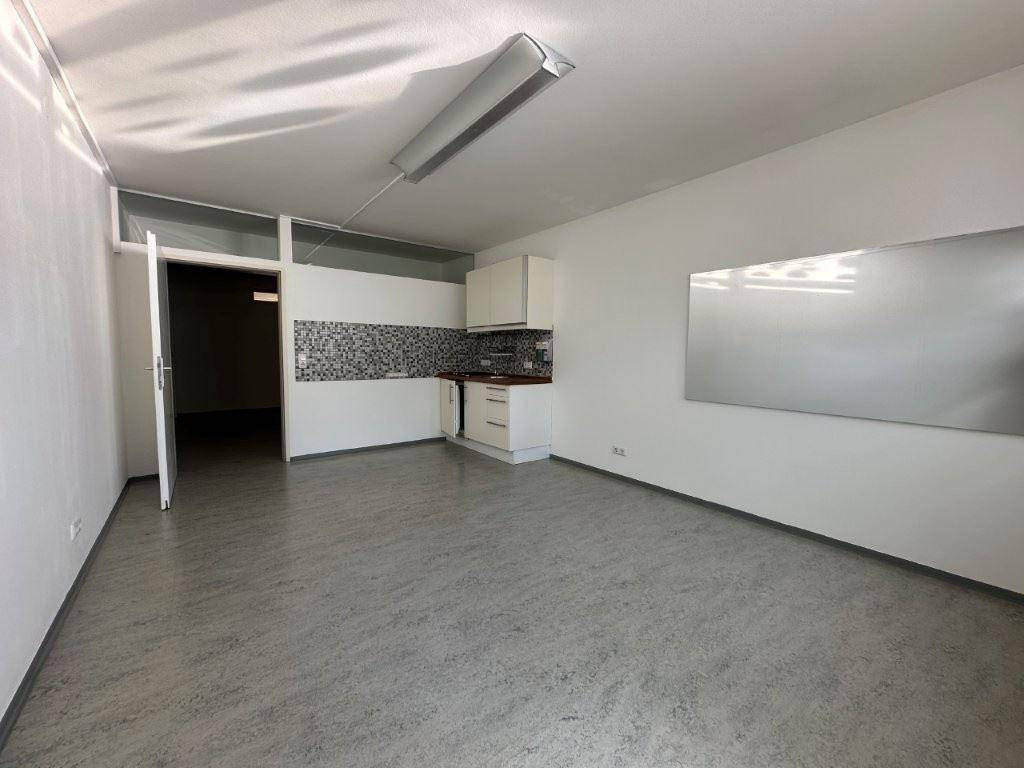 Heller Büroraum mit kleiner Küchenzeile, Linoleumboden und viel Tageslicht.