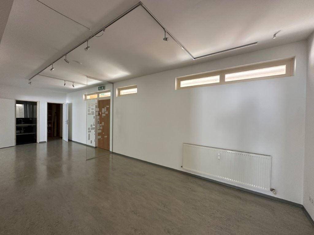 Langer Bürogang mit Linoleumboden, weißen Wänden und schmalen Fenstern für Tageslicht.