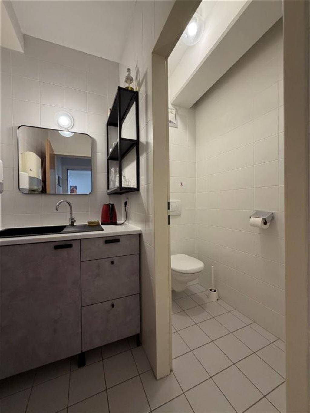 Modern geflieste Gästetoilette mit Waschbecken, Spiegel und Wand-WC.