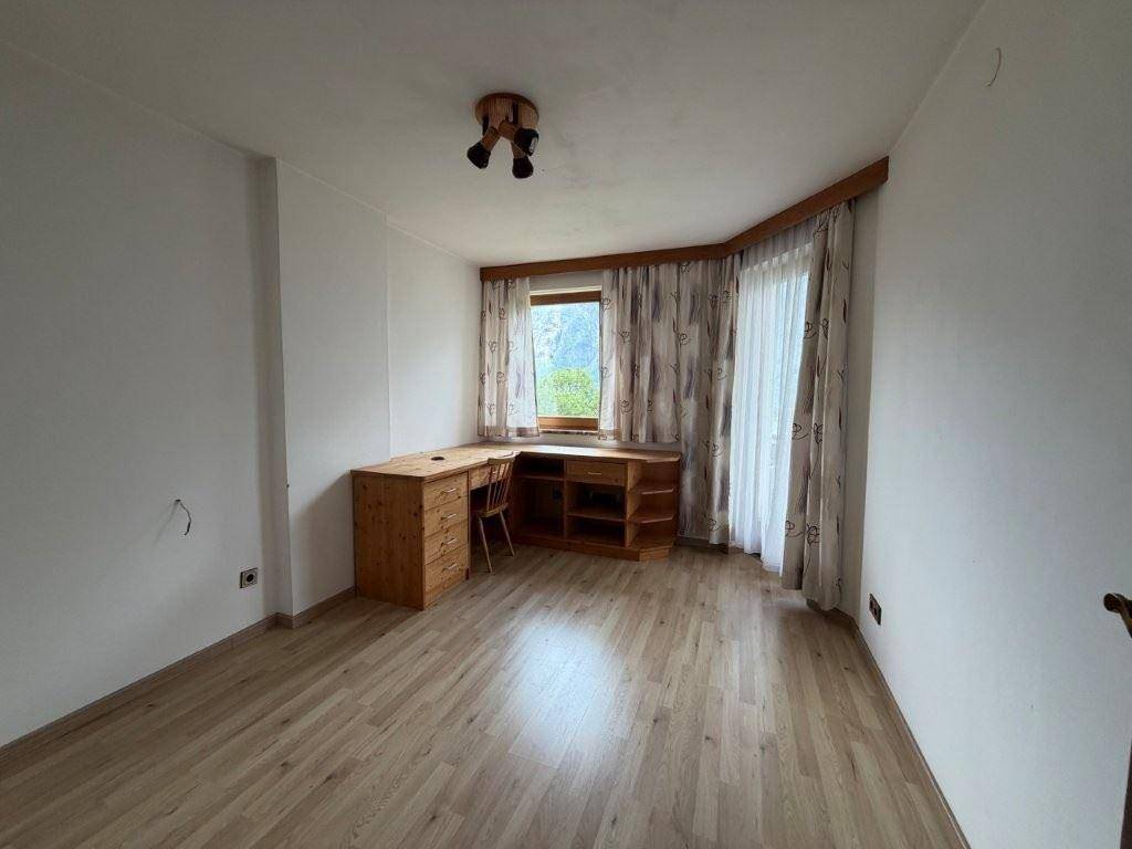 Helles Arbeitszimmer mit Holzschreibtisch, Laminatboden und Fenster mit Bergblick.