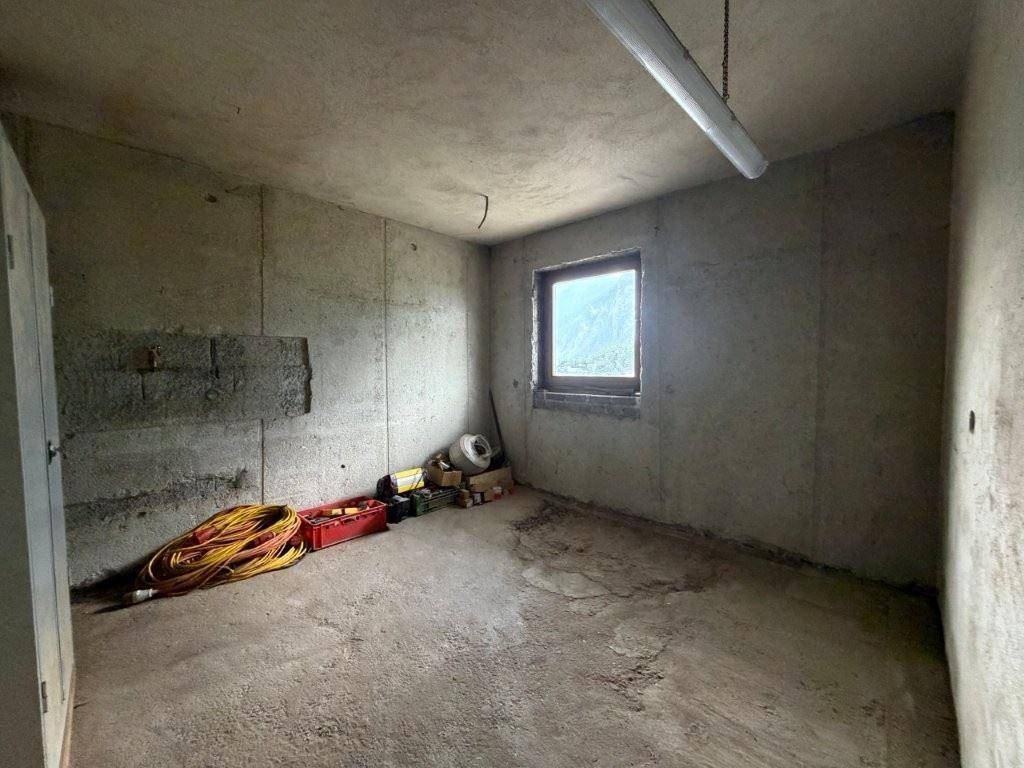 Lagerraum im Keller mit Betonwänden, Fenster und verschiedenen Baumaterialien.