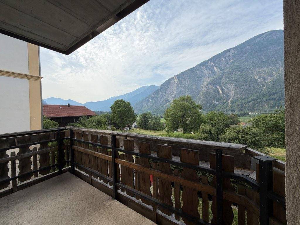 Balkon mit traditionellem Holzgeländer und weitem Blick über die grüne Landschaft.