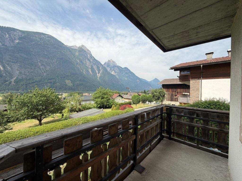 Geräumiger Balkon mit traditionellem Holzgeländer und Panoramablick auf die Berge.