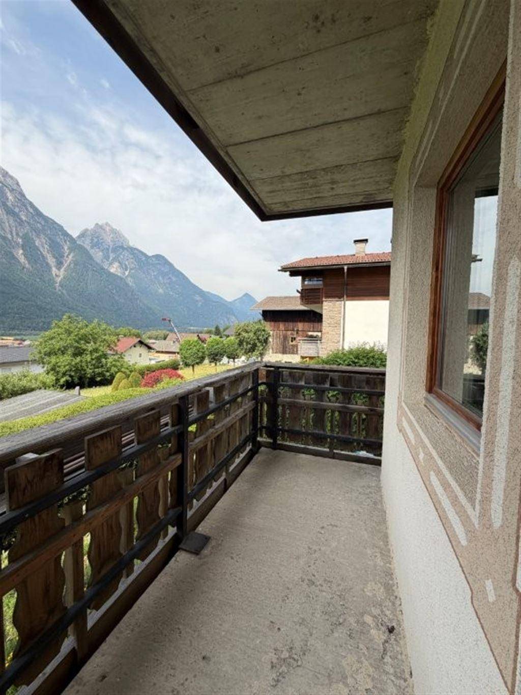 Balkon mit Holzbalkongeländer und weitem Blick auf die umliegende Berglandschaft.