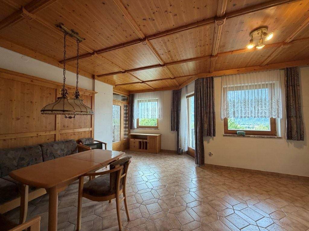 Geräumiges Wohnzimmer mit Holztäfelung, Holzdecke und traditionellem Fliesenboden.