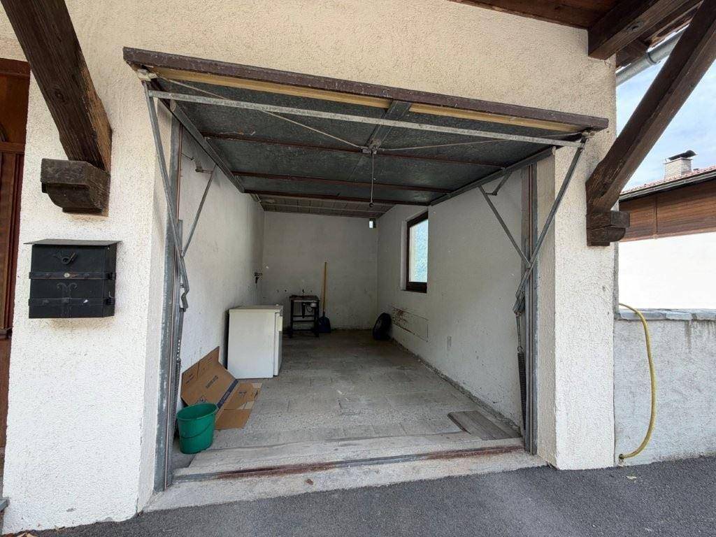 Einzelgarage mit offenem Tor, Fenster und Stauraum für verschiedene Gegenstände.