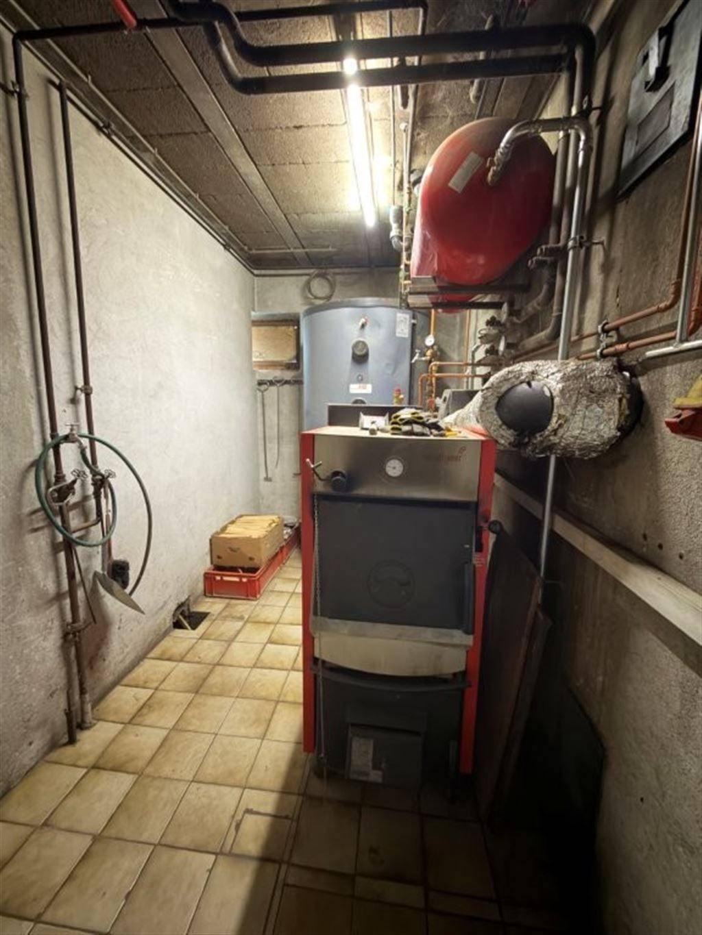 Heizungsraum mit Kessel, Warmwasserspeicher und sichtbaren Rohrleitungen.