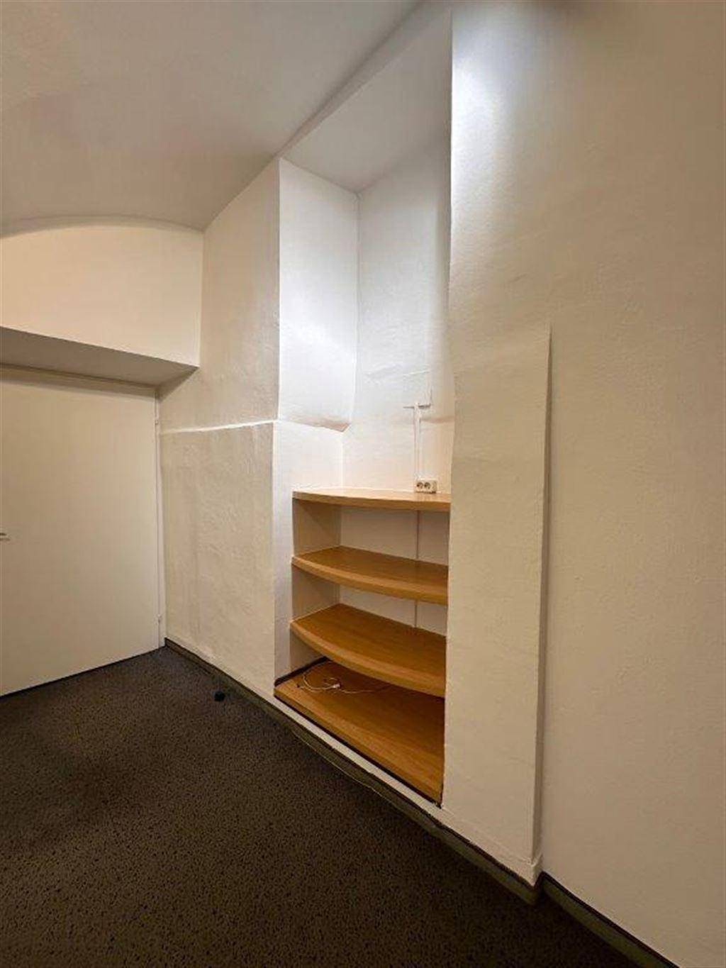 Kleiner Bereich mit eingebauten Holzregalen und weiß gestrichenen Wänden, ideal für Lagerung.