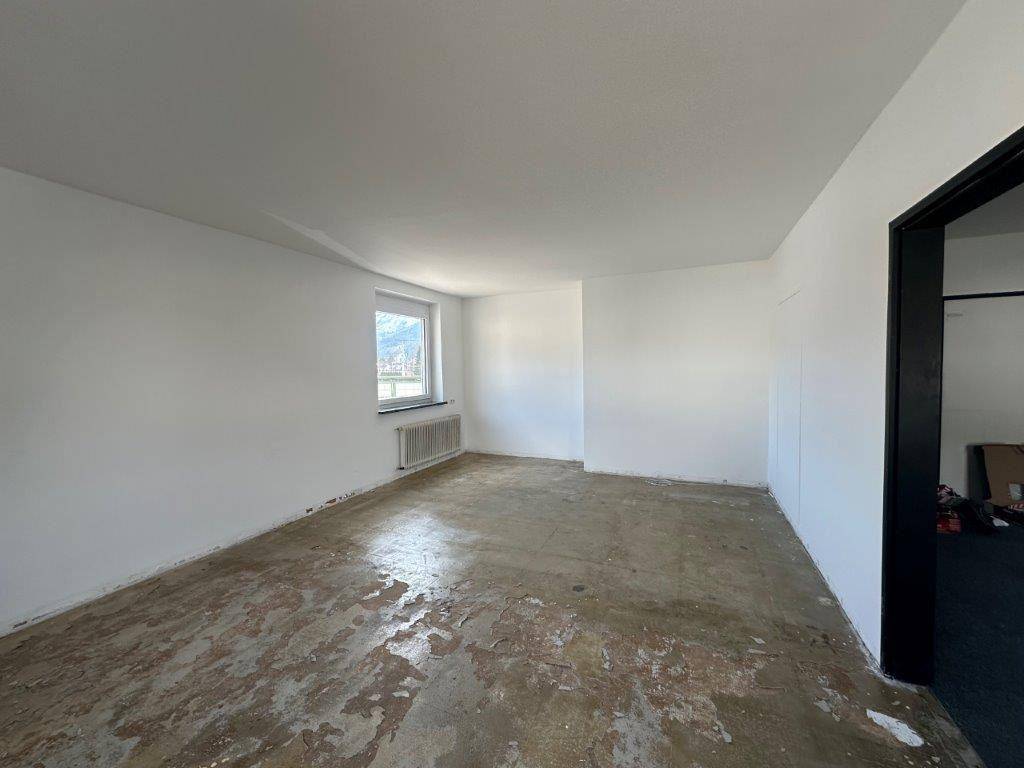 Renovierungsbedürftiger Raum mit freigelegtem Boden und einem Fenster mit Bergblick.