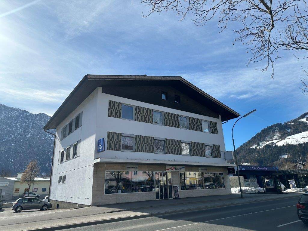 Mehrstöckiges Geschäftsgebäude mit traditionellem Dach und großen Schaufenstern an einer Straße gelegen.